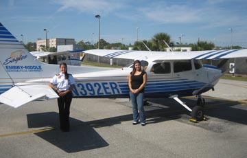 Two people standing beside a parked airplane